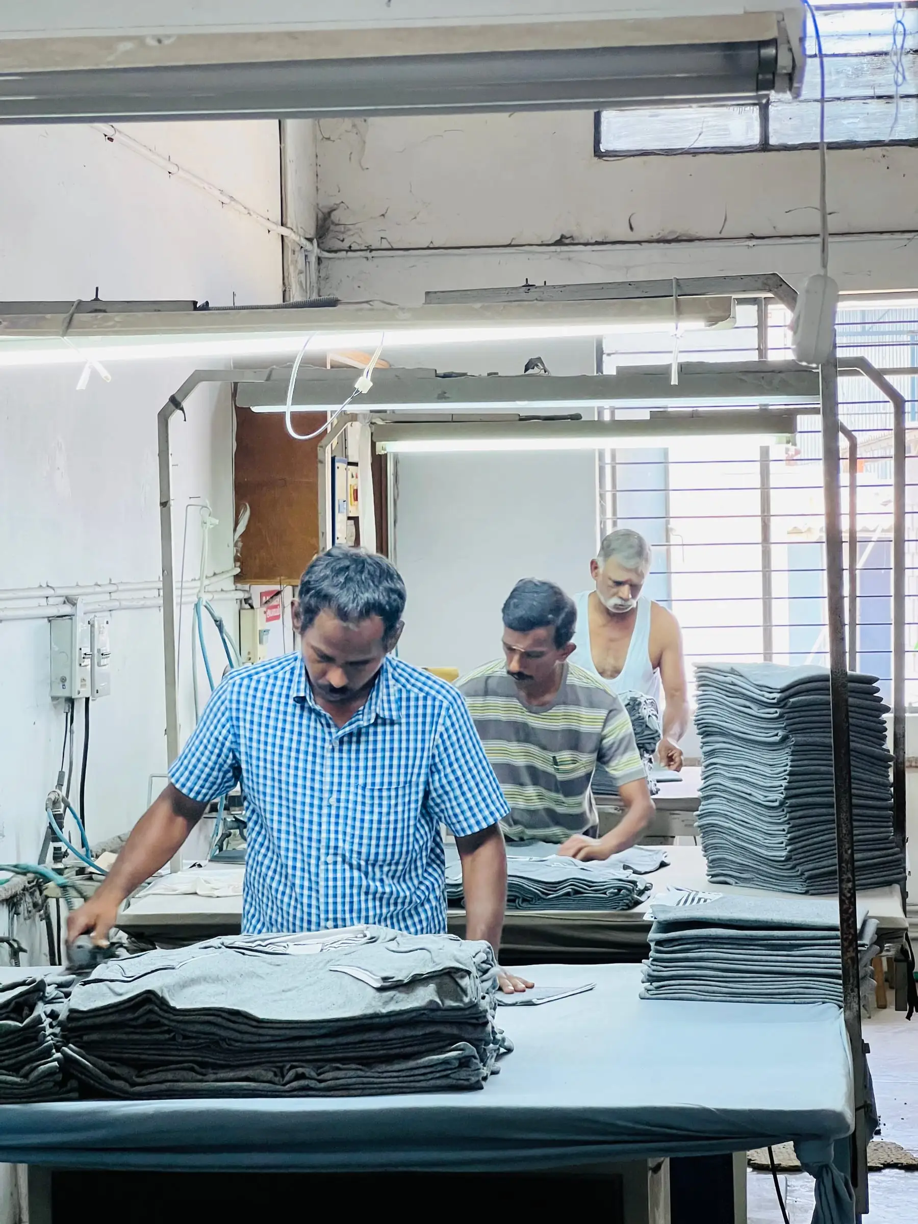 Two colleagues going through a finished run together, checking and stacking folded garments before it goes out.