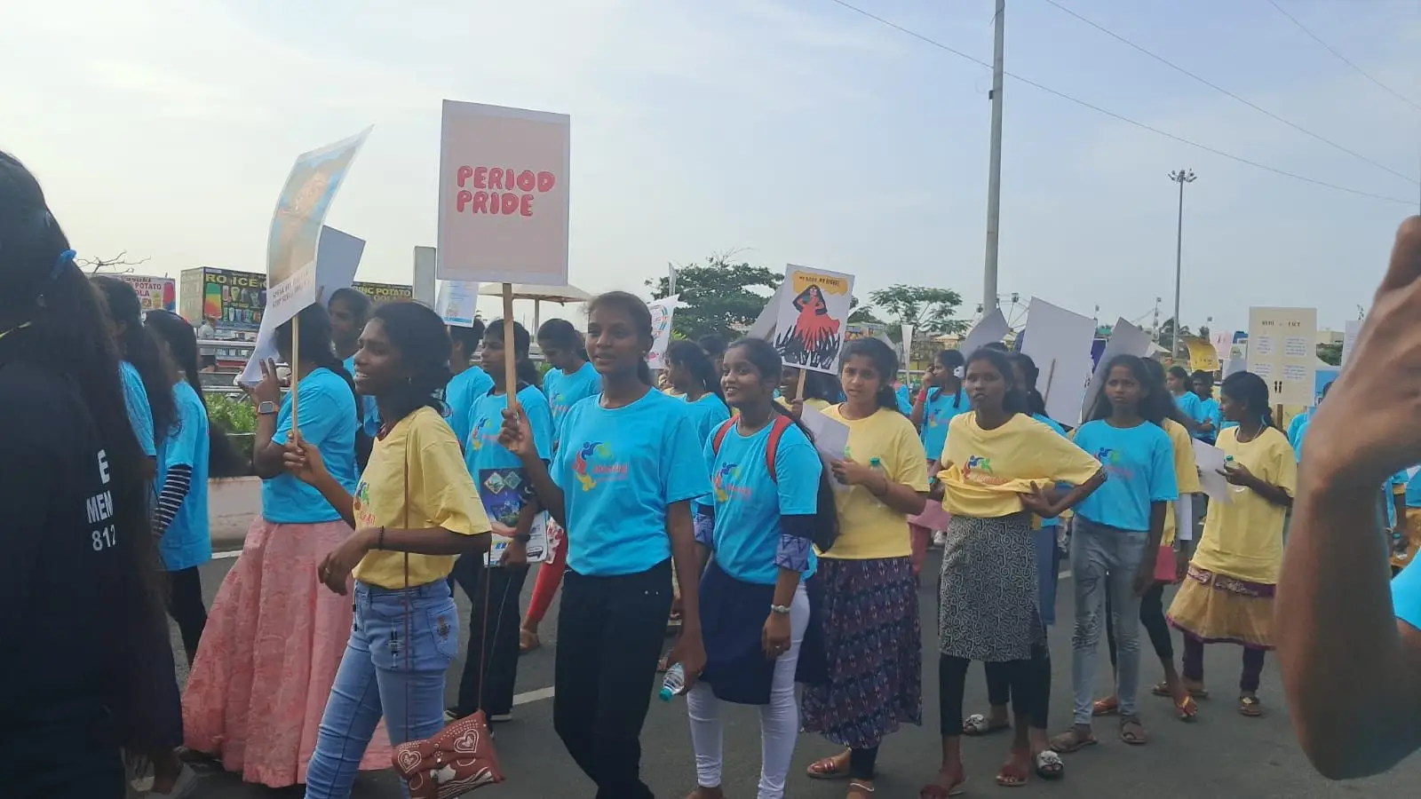 The CWDR march crowd in yellow and cyan t-shirts gathered on the road with banners.