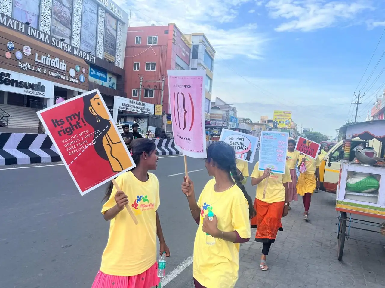 Women in yellow CWDR t-shirts walking a city road with awareness placards.