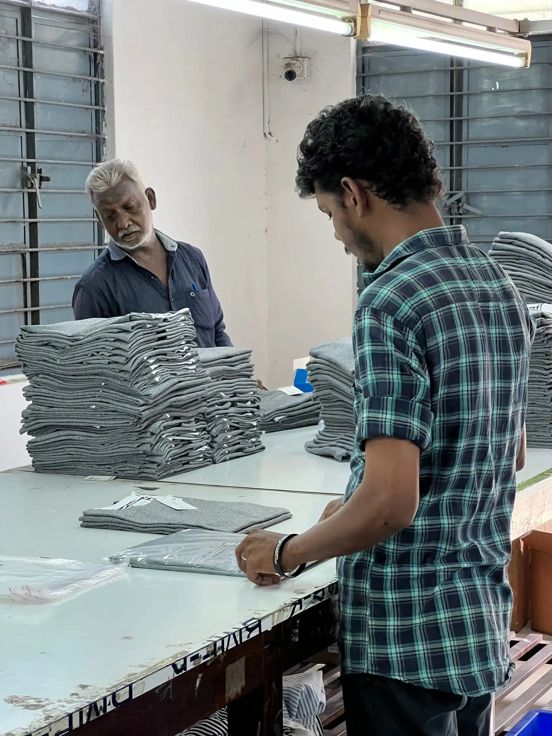 Finished garments being folded and stacked in even piles, ready for labelling and packing.