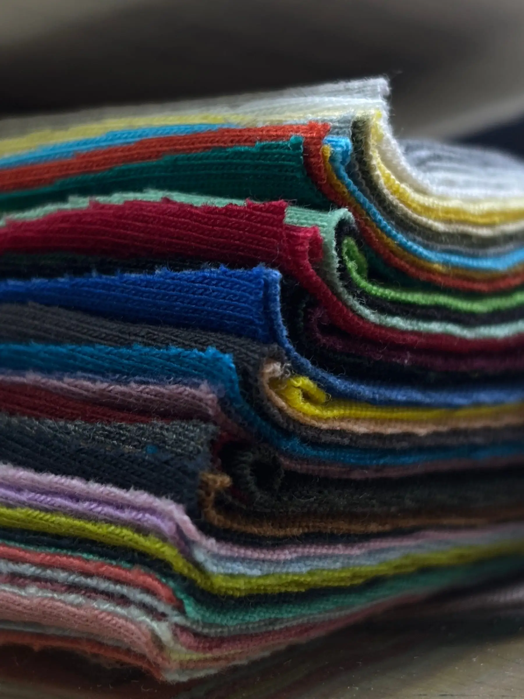 A stack of knitted fabric in a full colour range, cut edges showing the loop and the weight of the cloth.