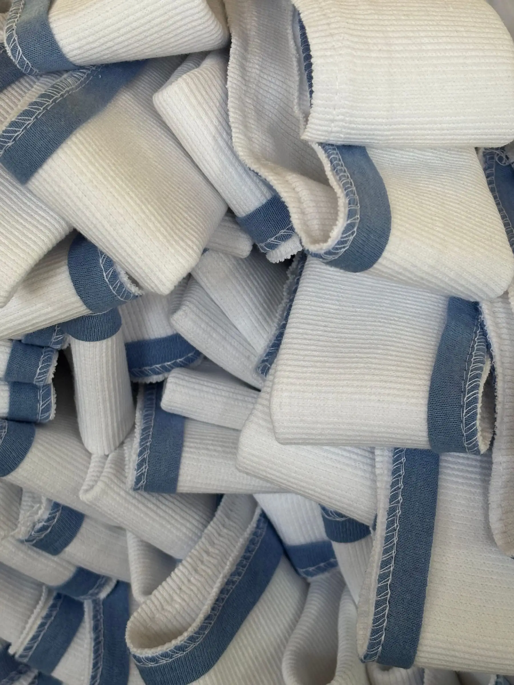 A pile of knitted rib trims in ecru with a navy stripe, cut and waiting for collars and cuffs.