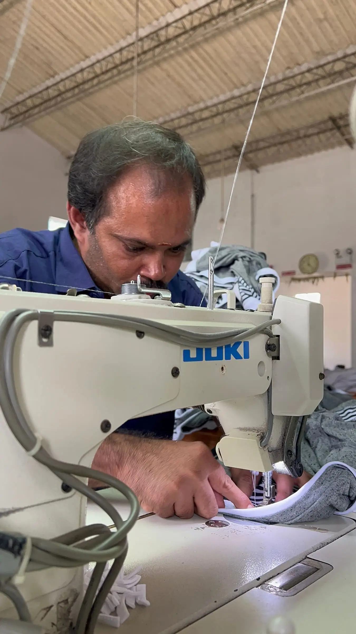 An operator at a single-needle machine, guiding a panel through the seam.